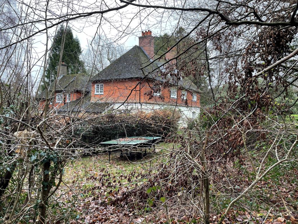 Lot: 94 - SUBSTANTIAL RESIDENTIAL INVESTMENT LET TO STATUTORY TENANT - Front and side view through the trees